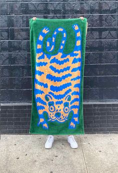 a person standing in front of a brick wall holding a towel with a tiger on it