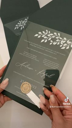 two hands holding up a wedding card with a gold seal on the front and bottom