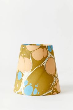 a lamp shade that has been painted with blue and orange designs on it's sides