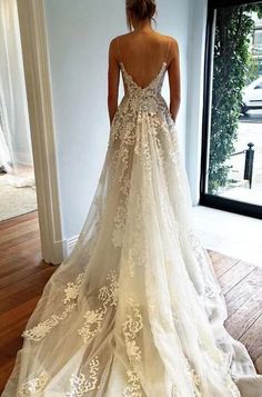 the back of a woman's wedding dress in front of a window