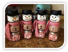 four mason jars with marshmallows and snowmen in them on a counter