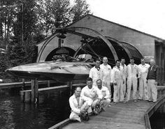 black and white photograph of men standing on dock next to boat