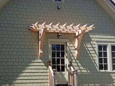 a white house with a wooden pergolan on the front door