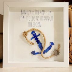 a white frame holding a blue and brown string with an anchor in the middle that says, family is teanchor that holds us through the storm