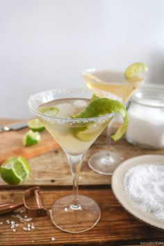 two martini glasses with limes and salt in them