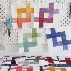 the quilts are hanging on the wall next to scissors