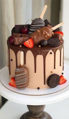 a chocolate covered cake with strawberries, cookies and other dessert items on top of it