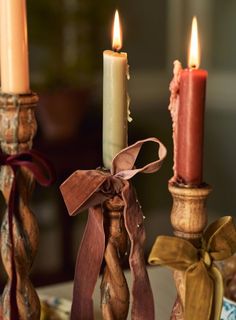 three candles with ribbons on them sitting next to each other in front of a table