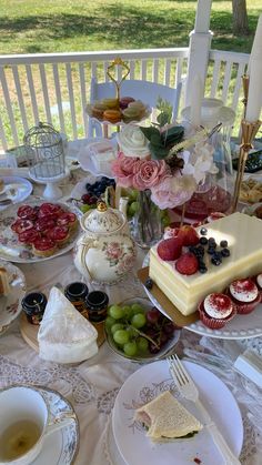 a table topped with plates and cups filled with desserts on top of a white table cloth