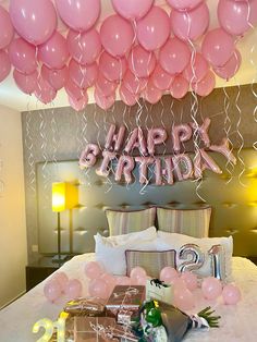 a bed with pink balloons and gifts on it, along with the words happy birthday