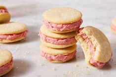 several cookies with pink frosting are stacked on top of each other and one cookie has been cut in half