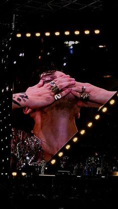 a man with his hands on his face in front of a mirror that has lights around him