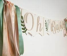 a banner with ribbons hanging from it's sides and the word oh baby spelled in cursive letters