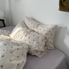 an unmade bed with several pillows on top of it in a white walled room