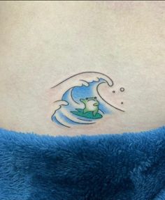 a woman's stomach with a small tattoo of a frog on top of a wave