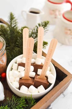 marshmallows are arranged in a bowl on a tray next to some mugs