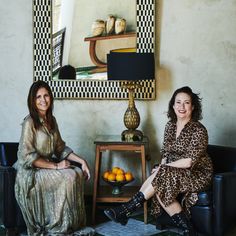 two women sitting on couches next to a table with oranges in front of them