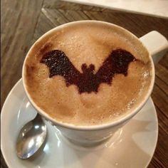 a cappuccino with a bat drawn on the foam in it's cup