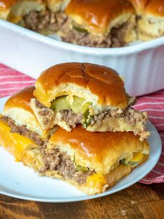 two sandwiches on a plate next to a casserole dish filled with meat and cheese