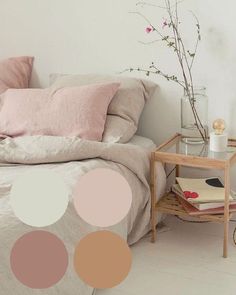 a bed with pink and white pillows on top of it next to a small table