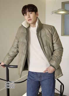 a young man standing next to a stair rail wearing a jacket and jeans with a fur collar