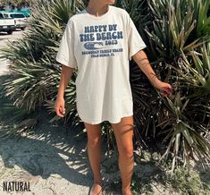 Introducing our vintage inspired "Happy by the Beach" Custom Beach Vacation Shirts perfect for your next beach getaway. Customize any of the text on this shirt by entering your request in the personalization box prior to check out. We use professional quality DGT printing on all our apparel. Direct-to-garment, or DTG, is a high quality printing method that sprays ink directly onto the garment so there is no peeling or cracking. This fabulous graphic will be printed on a Bella+Canvas Unisex Tee. Order your regular size for a slim fit and size up for an oversized fit. Please refer to the size charts in the images to find your ideal fit.  Production Time: 1-5 days Shipping Time: 2-5 days Machine wash: cold  Non-chlorine: bleach as needed Tumble dry: low heat Iron, steam or dry: medium heat Do Zach Bryan Shirt, Vacation Tshirts, Ocean Shirt, Pink Skies, Camp Counselor, Zach Bryan, T Shirt Oversize, Coastal Cowgirl, Beach T Shirts