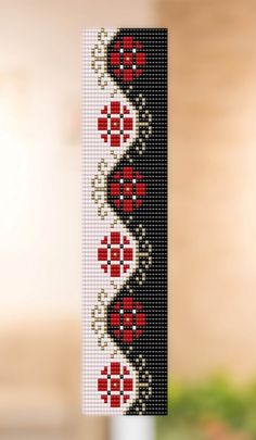 a cross - stitch decoration with red flowers is hanging from a hook on the wall