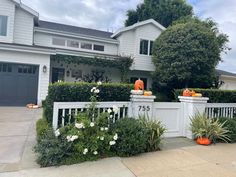 a white house with pumpkins on the fence