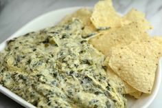 a white bowl filled with spinach dip and tortilla chips