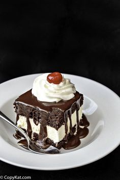 a piece of cake on a white plate with chocolate sauce and whipped cream drizzled around it