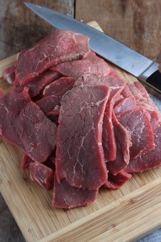 raw meat is cut up on a cutting board with a knife