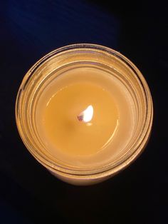 a lit candle in a glass bowl on a table