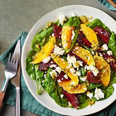 a salad with beets, feta cheese and spinach leaves on a white plate