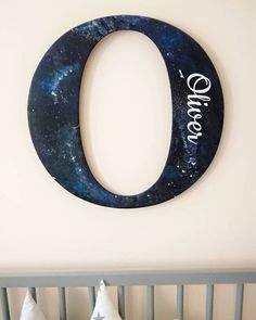 a baby's room with a crib, bed and wall hanging in the shape of an o