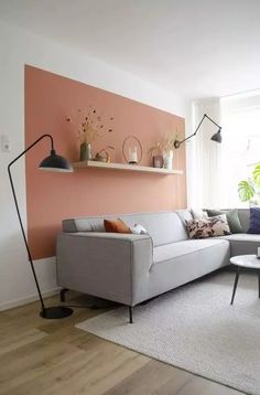 a living room with pink walls and white furniture in the corner, including a gray sectional sofa