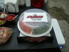 a table topped with a plastic container filled with veggies next to bowls of food