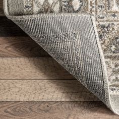 an area rug on the floor with wooden floors and wood planks in the background