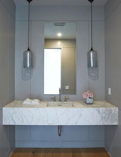 a bathroom with marble counter tops and two hanging lights