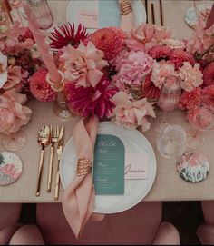 the table is set with pink flowers and place settings