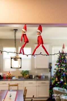 two elfs hanging on a string in front of a christmas tree