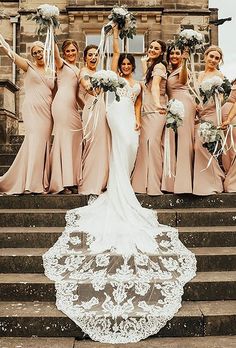 a group of women standing next to each other in front of stairs holding bouquets