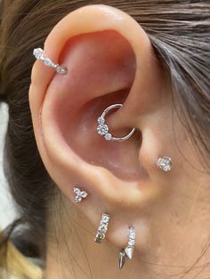 a woman wearing three different types of ear piercings