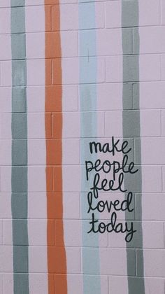 the words make people feel loved today are painted on a brick wall with multicolored stripes