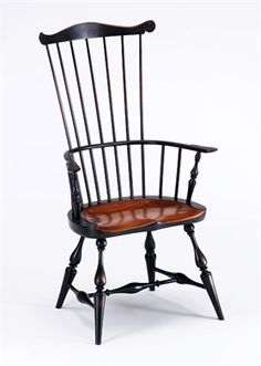 an old fashioned black and brown rocking chair with wood seat padding on the back