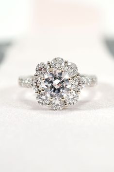 an engagement ring with three stone halos in the center, on a white surface