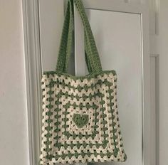 a green and white crocheted bag hanging on a door