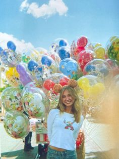 a woman standing in front of a bunch of balloons