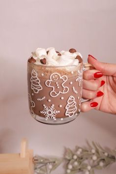 a woman is holding a cup of hot chocolate and marshmallows in it