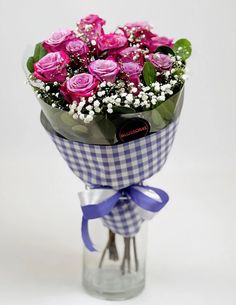 a bouquet of pink roses in a clear vase on a white tablecloth with blue ribbon