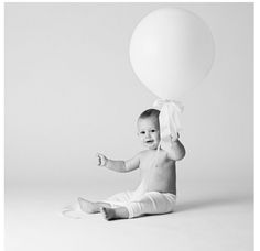 a baby sitting on the floor with a balloon